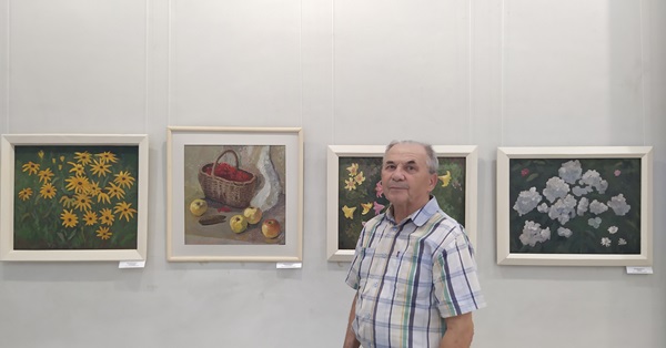 Художник Валерий Манаенков на фоне своих работ